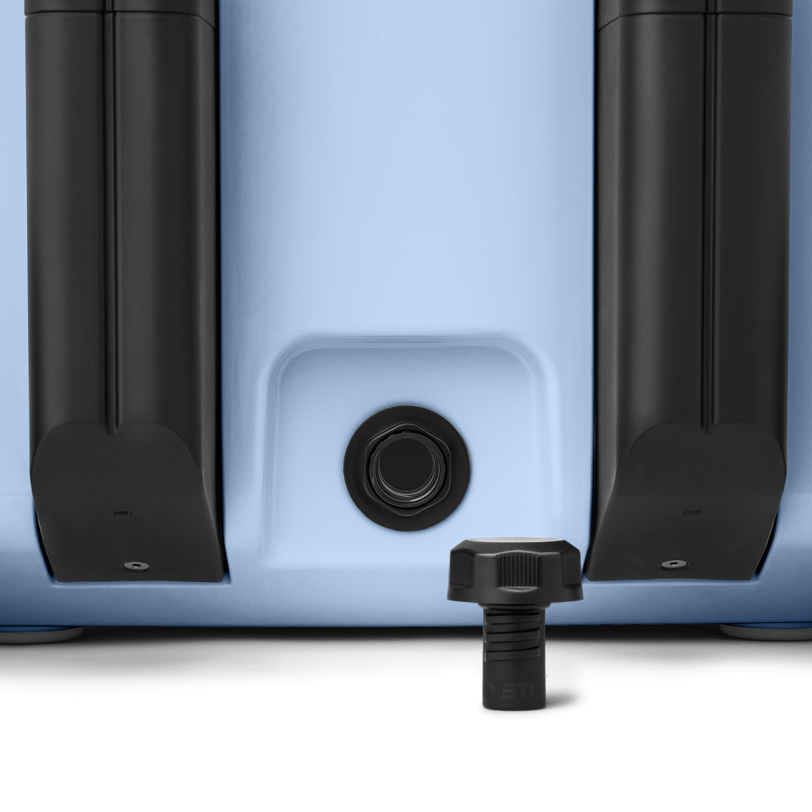 Nahaufnahme des Bodens der YETI® Kühlbox Roadie 32 in Big Sky Blue, wobei die beiden schwarzen Räder und die zentrale Ablassschraube mit dem schwarzen Gewindedeckel im Vordergrund hervorgehoben werden.