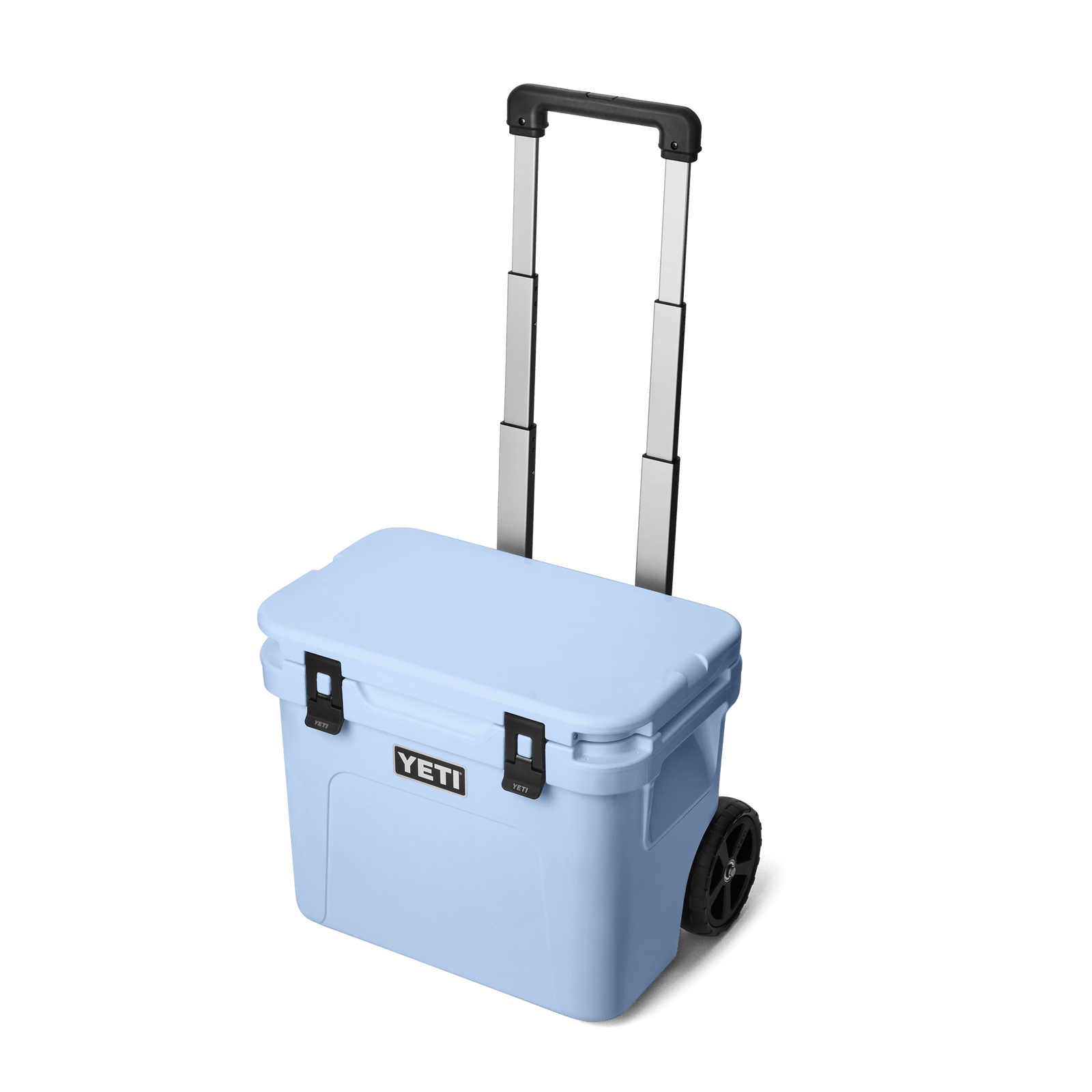 Die YETI® Kühlbox Roadie 32 in Big Sky Blue verfügt über schwarze Verschlüsse, Räder und einen Teleskopgriff für den einfachen Transport.