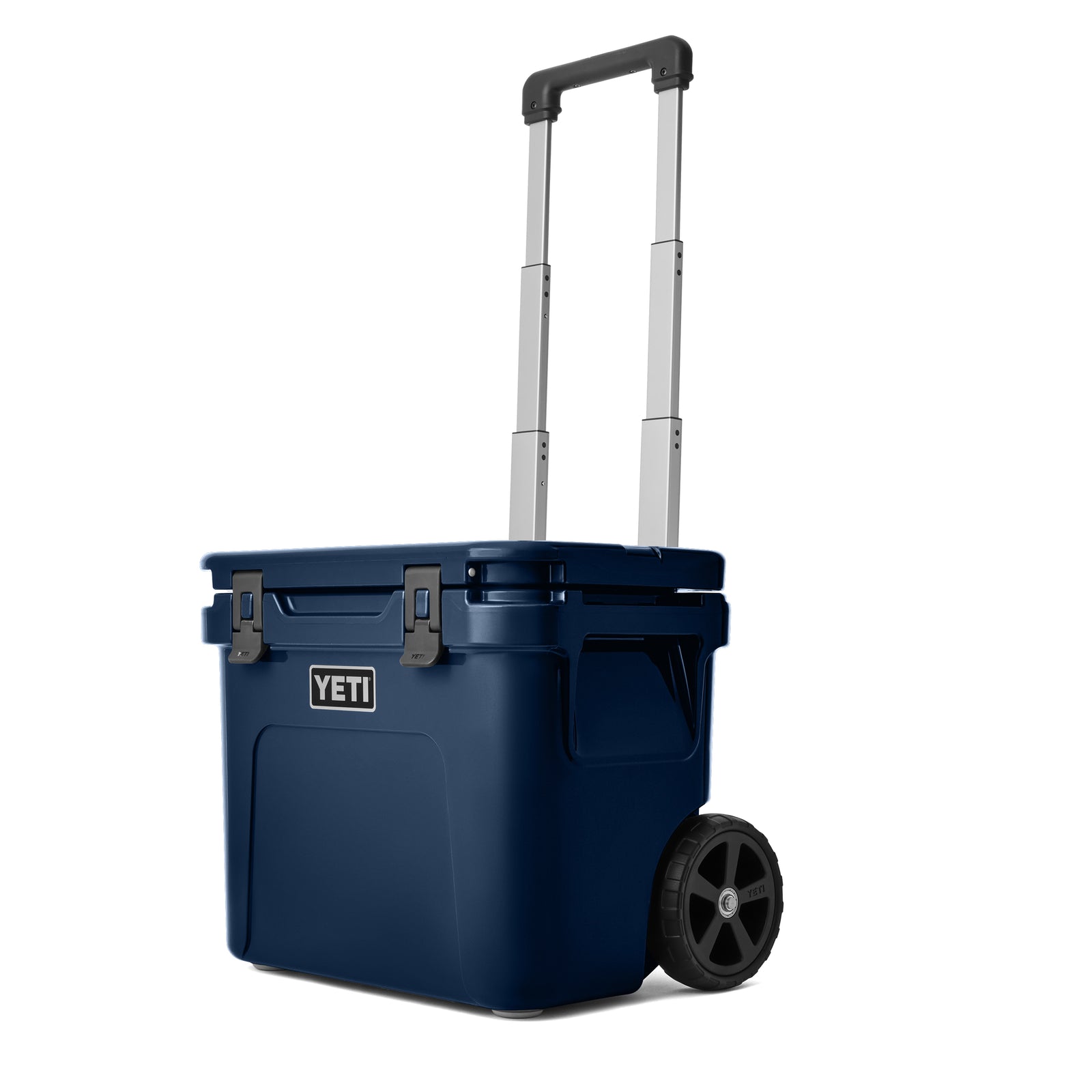 Die YETI® Kühlbox Roadie 32 - Navy von YETI ist auf weißem Hintergrund abgebildet - sie verfügt über ausziehbaren Griff, zwei schwarze Verschlüsse sowie zwei große schwarze Räder.