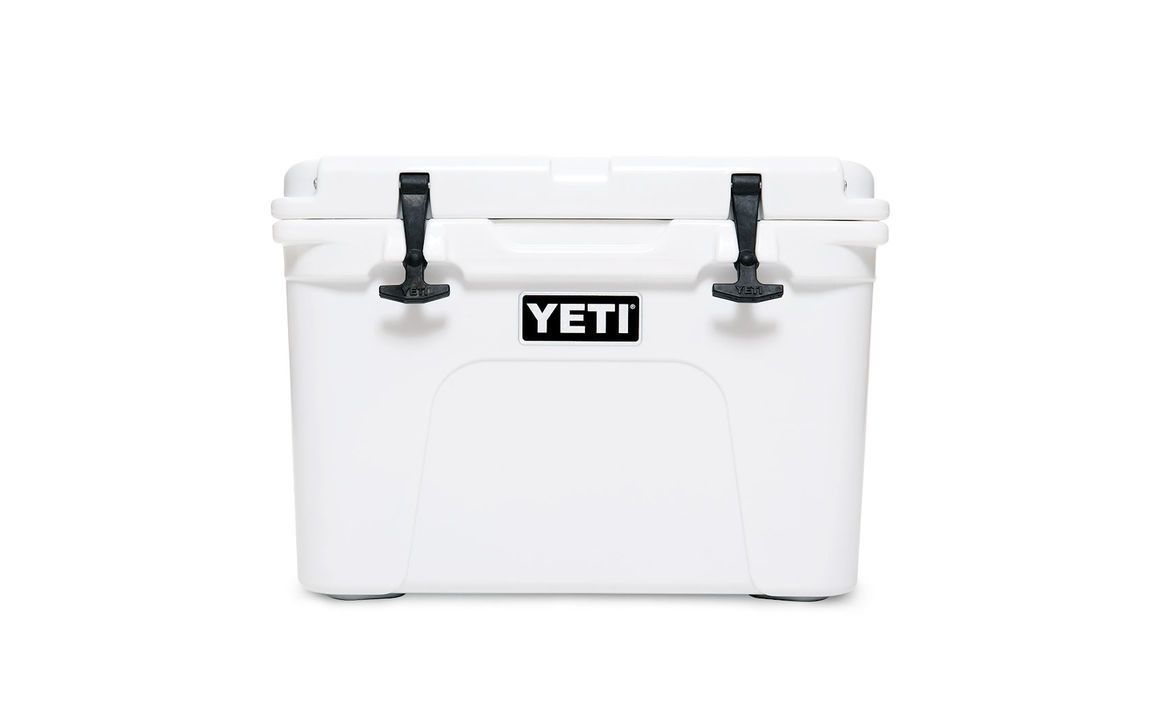Die YETI® Kühlbox Tundra 35 - White hat schwarze Verschlüsse und ein auffälliges YETI-Logo auf der Vorderseite; diese robuste Kühlbox ist auf einem schlichten weißen Hintergrund abgebildet.