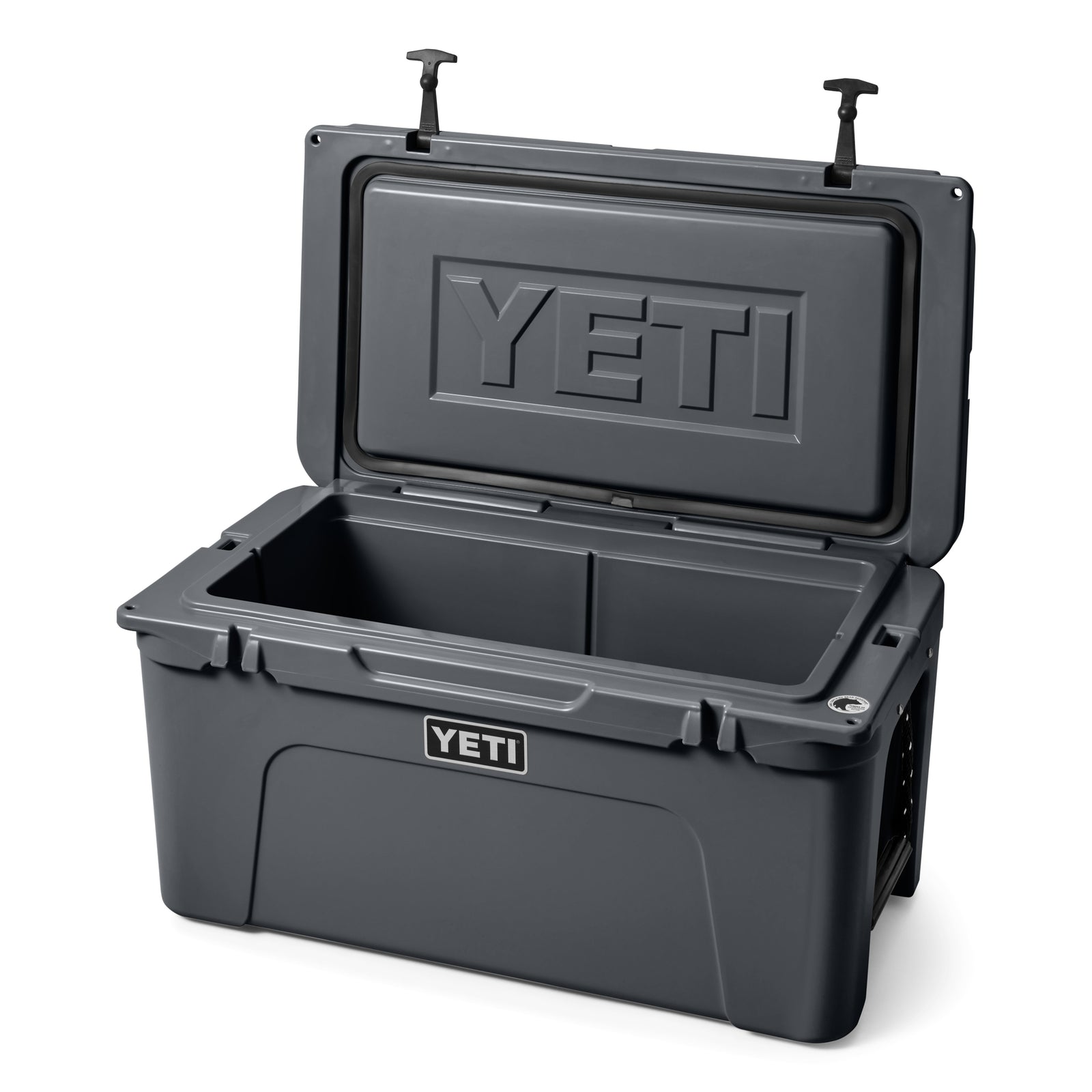 Die YETI® Kühlbox Tundra 65 - Charcoal ist geöffnet abgebildet und zeigt ihren geräumigen, leeren Innenraum - ideal für das Camping - mit dem YETI-Logo auf der Innenseite des Deckels und auf der Vorderseite.