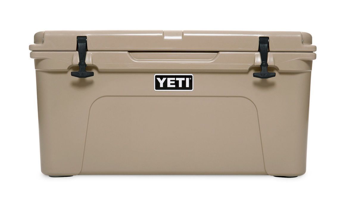Die YETI® Kühlbox Tundra 65 in Tan hat eine rechteckige Form, schwarze Verschlüsse, ein zentriertes YETI-Logo und ein robustes Design, das auf weißem Hintergrund dargestellt ist.
