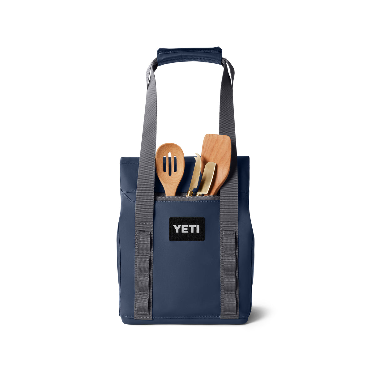 Eine YETI® Kühltasche Daytrip Lunch Bag 14L - Navy, mit grauen Griffen und Coldcell Flex-Isolierung, ist mit hölzernen Kochutensilien wie einem Schaumlöffel und Pfannenwender gefüllt, die von oben sichtbar sind.
