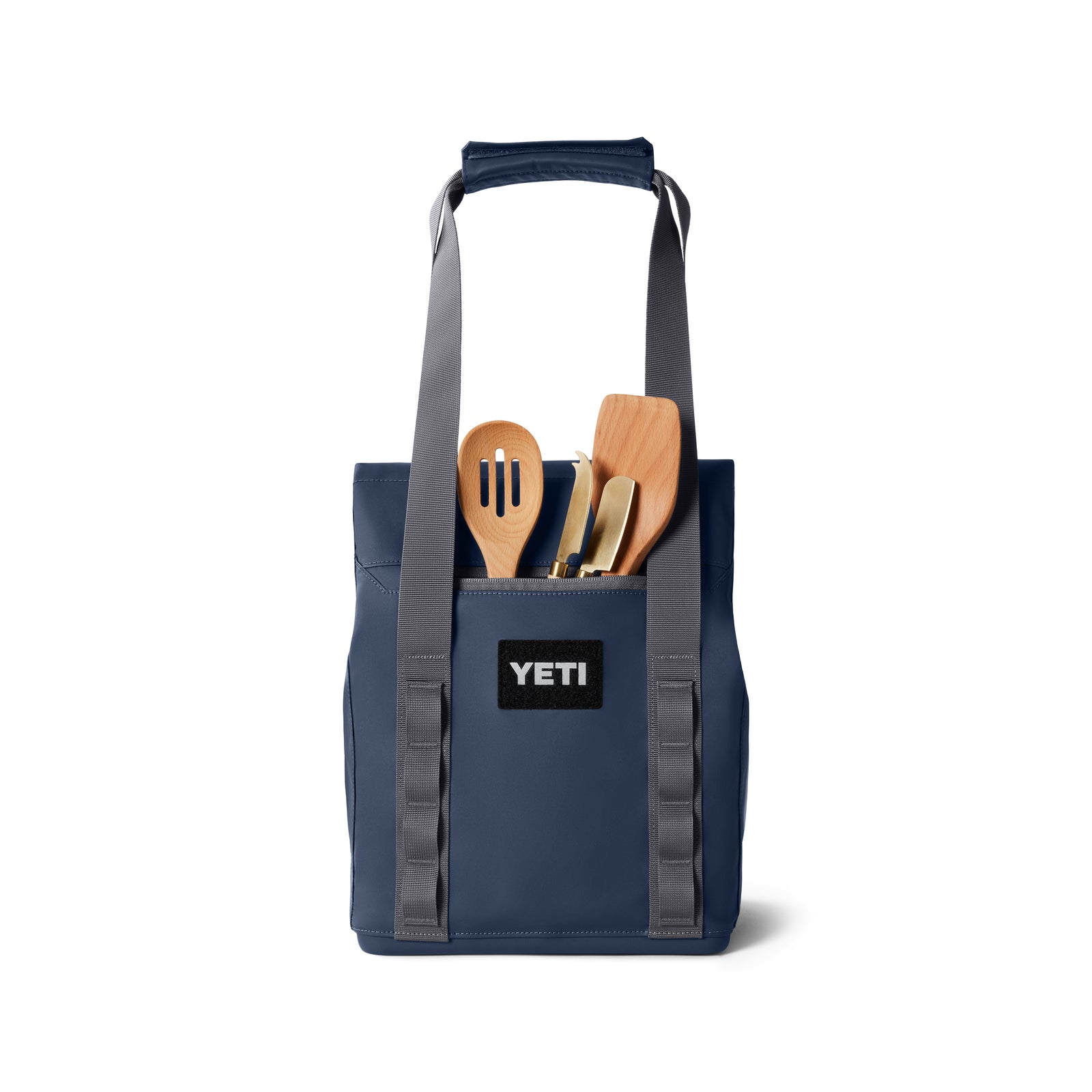 Eine YETI® Kühltasche Daytrip Lunch Bag 14L - Navy, mit grauen Griffen und Coldcell Flex-Isolierung, ist mit hölzernen Kochutensilien wie einem Schaumlöffel und Pfannenwender gefüllt, die von oben sichtbar sind.