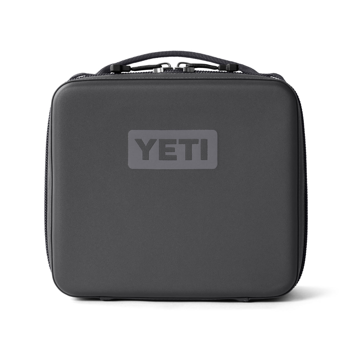 Eine schwarze YETI® Kühltasche Daytrip Lunch Box 3L in Charcoal mit Tragegriff und grauem YETI-Logo auf der Vorderseite, fotografiert vor einem schlichten weißen Hintergrund.