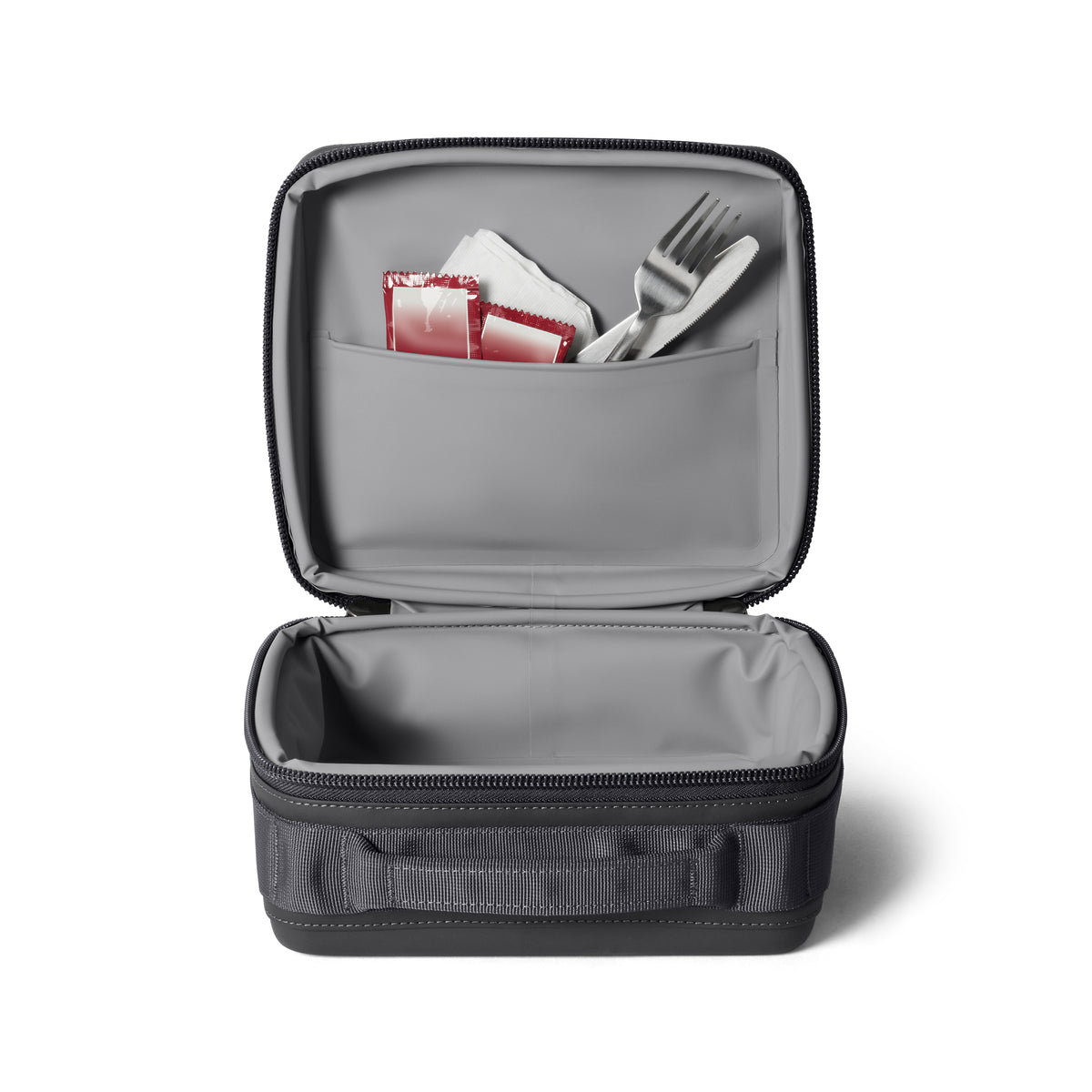 Die YETI® Kühltasche Daytrip Lunch Box 3L - Charcoal steht auf einem weißen Hintergrund. Die obere Tasche fasst zwei Gewürzpakete, eine Gabel und einen Löffel; das untere Fach ist leer und zeigt ColdCell Flex Isolierung für dauerhafte Frische.