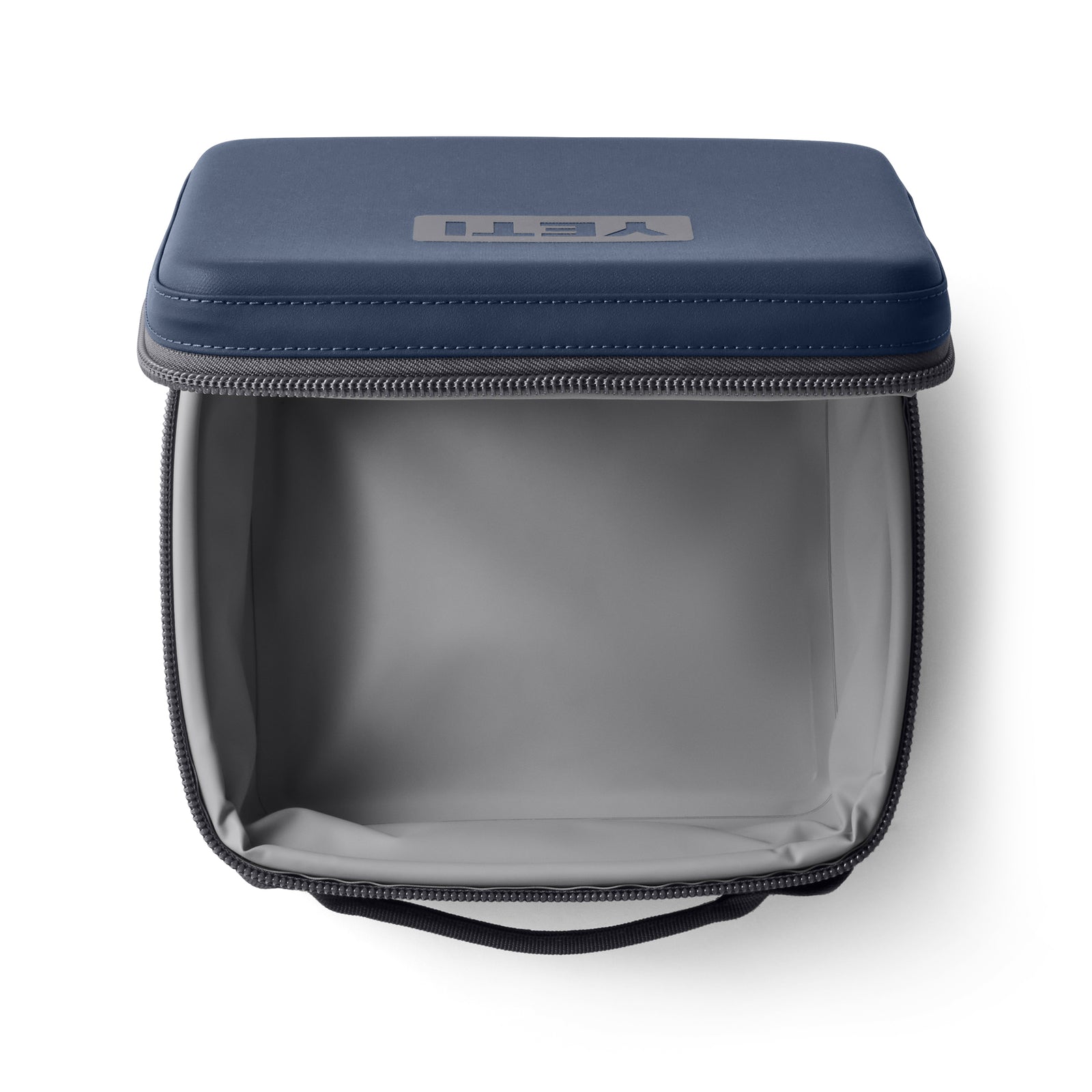 Blick von oben auf eine geöffnete, leere YETI® Kühltasche Daytrip Lunch Box 3L in Navy, mit hellgrauem Innenraum und sichtbarem Markenlogo auf dem Deckel. Der Reißverschluss ist offen, so dass die Kühlhaltefunktion sichtbar ist.