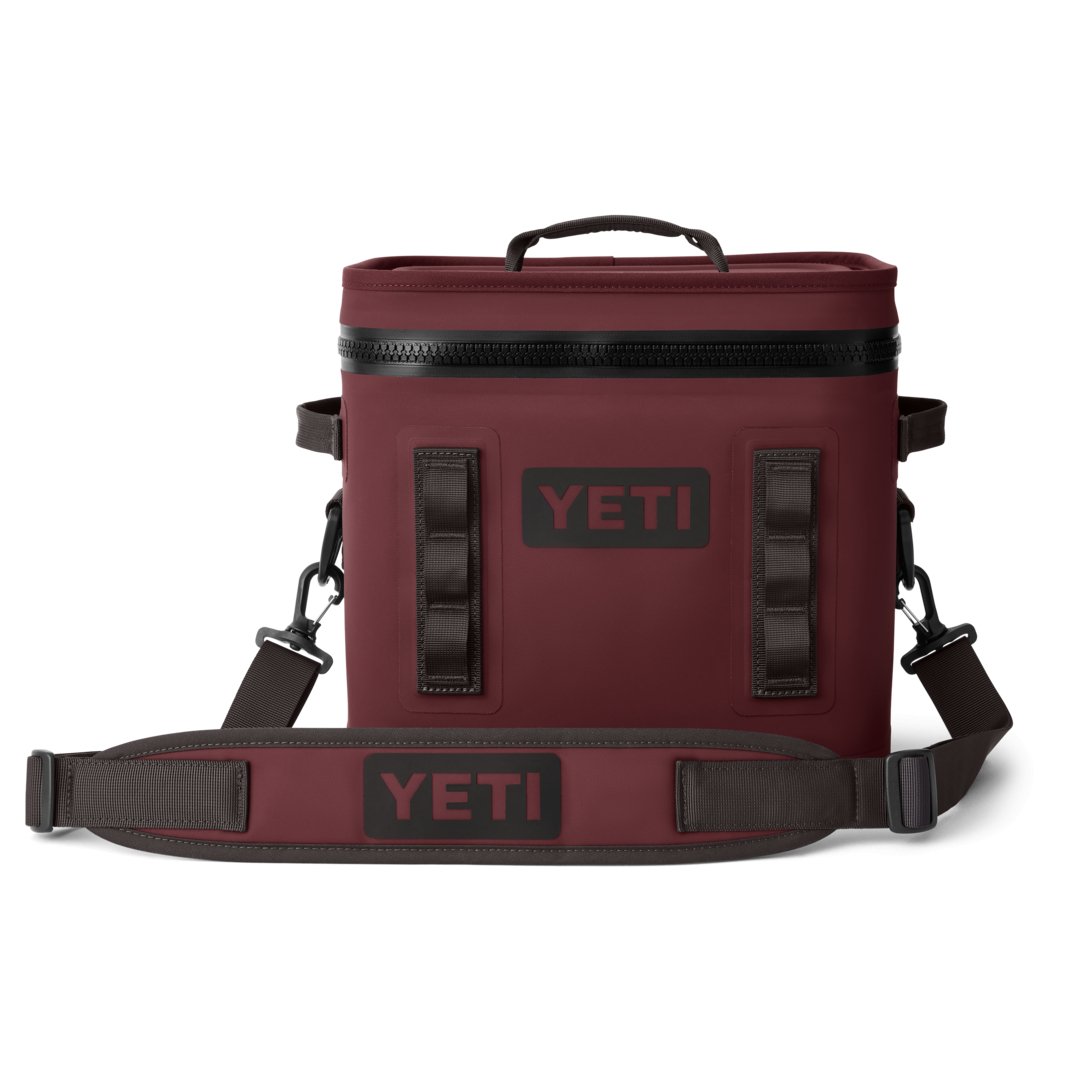 Die YETI® Kühltasche Hopper Flip® 12 in Wild Vine Red hat einen Reißverschluss oben, schwarze Griffe und einen verstellbaren Schultergurt mit dem YETI-Logo auf weißem Hintergrund.