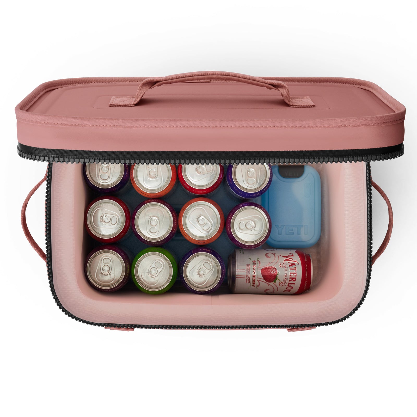 Draufsicht auf eine geöffnete YETI® Kühltasche Hopper Flip® 18 - Sandstone Pink mit zwölf Getränkedosen, einer Waterloo-Sprudeldose und einem blauen YETI-Kühlpack.