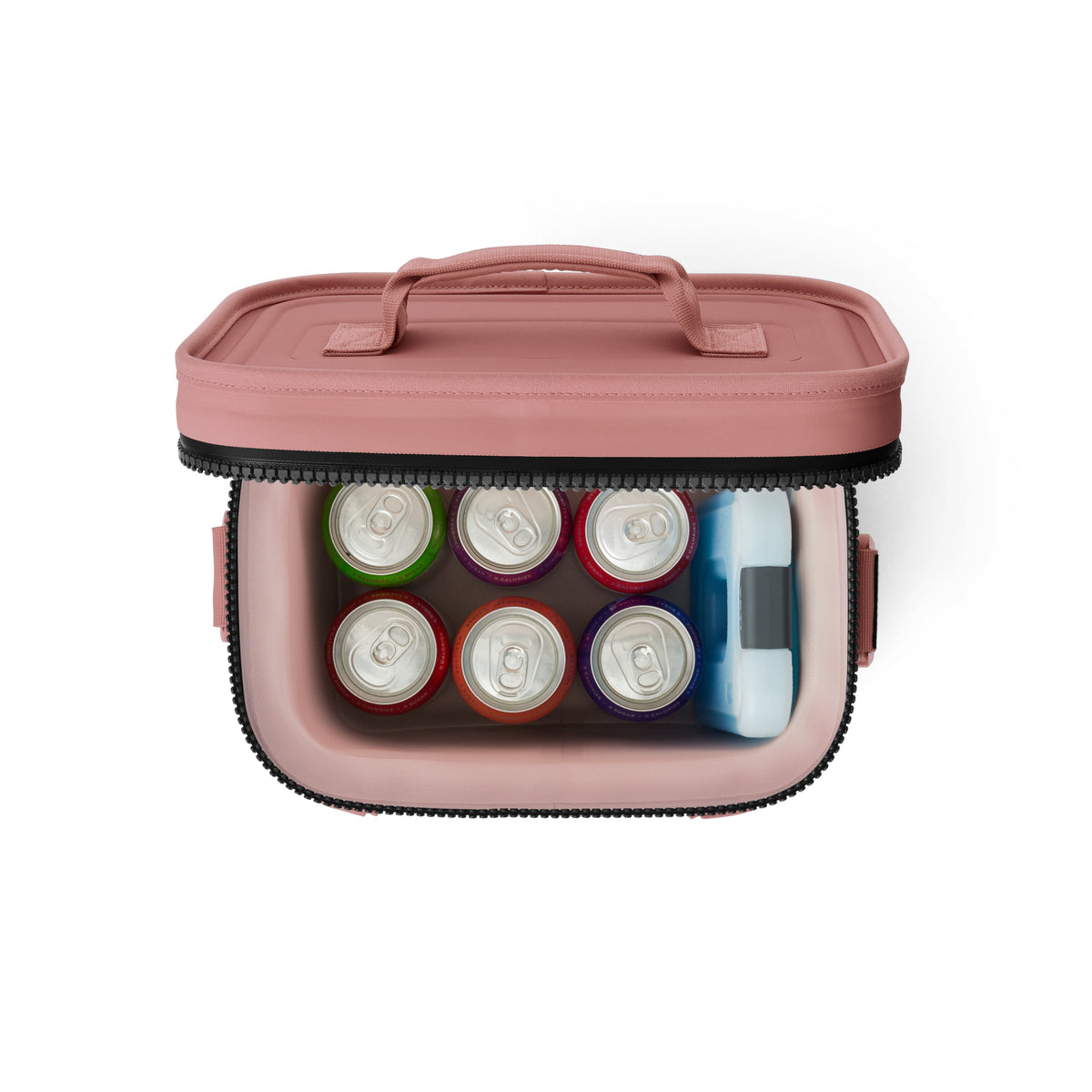 Eine Draufsicht auf eine YETI® Kühltasche Hopper Flip® 8 - Sandstone Pink zeigt sie geöffnet und gibt den Blick frei auf acht Getränkekonserven, die in zwei Reihen angeordnet sind und einen blau-weißen Eisbeutel an der Seite haben.