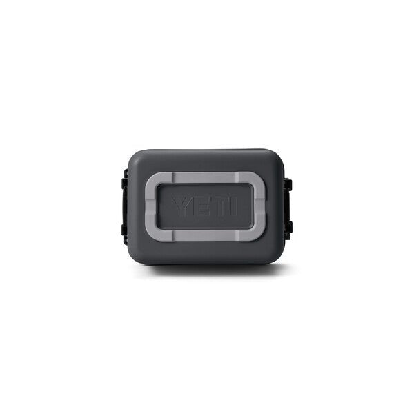 Die YETI® LoadOut GoBox 15 - Charcoal ist eine dunkelgraue, rechteckige Getriebebox mit schwarzen Seitenverschlüssen, einem hellgrauen Rahmen um das YETI-Logo und einem robusten, wasserfesten Design auf weißem Hintergrund.
