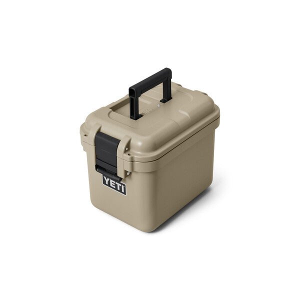 Die YETI® LoadOut GoBox 15 in Tan mit schwarzem Griff und Frontverschluss ist auf einem weißen Hintergrund abgebildet. Das YETI-Logo unterstreicht diese robuste Tasche, die für den sicheren Transport von Ausrüstung konzipiert ist.