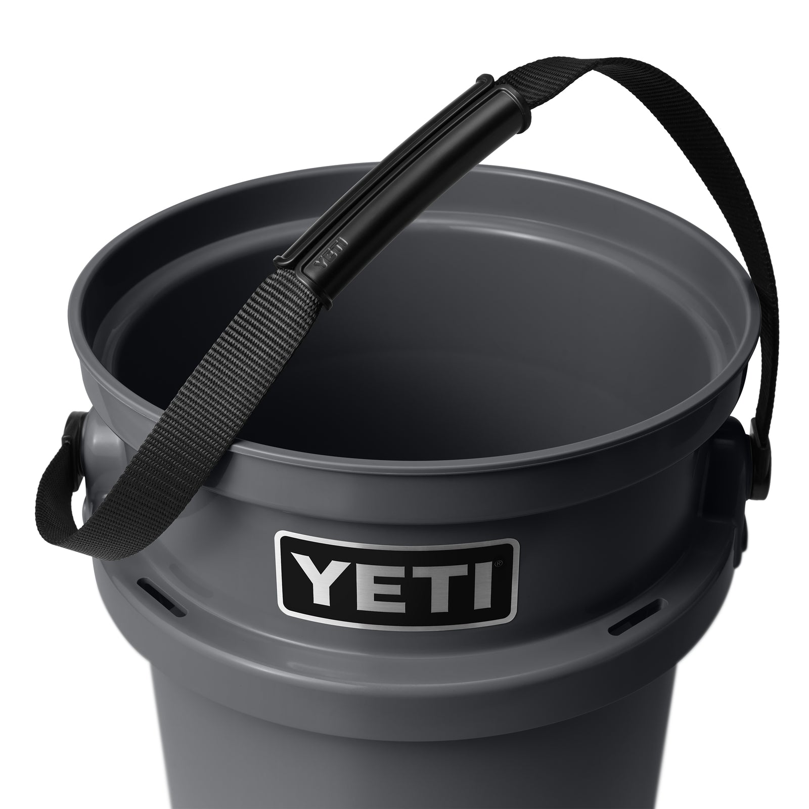 Eine Nahaufnahme des YETI® Loadout Eimer 19 Liter in Charcoal mit robustem schwarzem Griff und Nylongurt. Das YETI-Logo prangt auf diesem robusten Outdoor-Eimer, der ideal für jedes Abenteuer ist.
