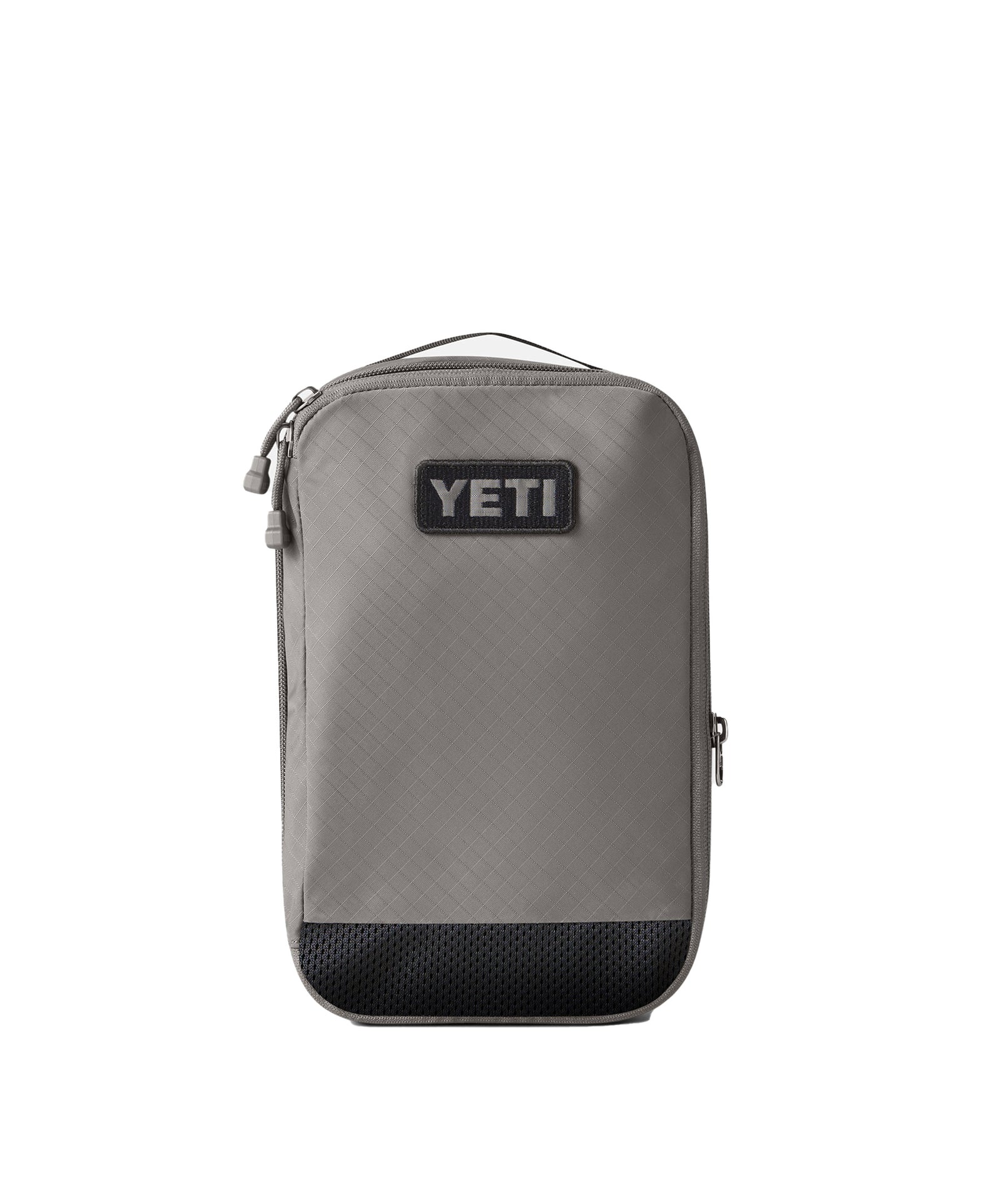 Die YETI® Packtaschen - Crossroads Cubes M in Grau ist ein rechteckiger Packwürfel mit einem Reißverschluss und einem schwarzen Logoaufnäher auf der Vorderseite sowie einer strukturierten schwarzen Bodenplatte. Er ist ideal für die Organisation von wichtigen Dingen und wurde vor einem weißen Hintergrund fotografiert.