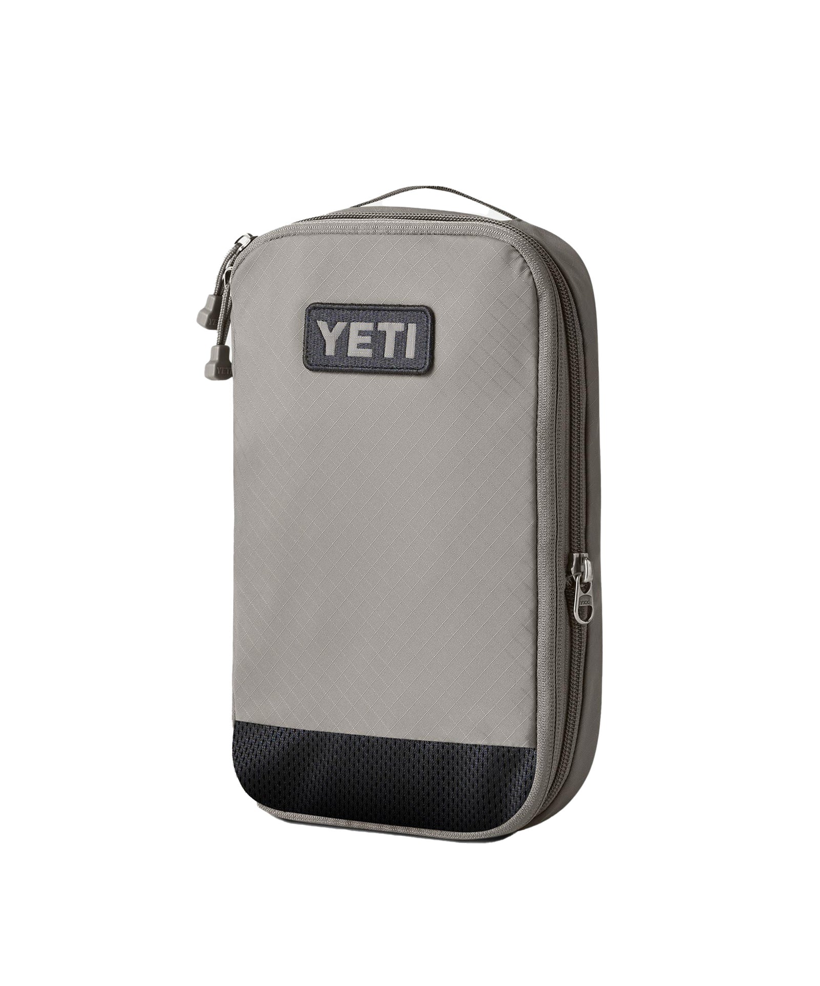 Die YETI® Packtaschen - Crossroads Cubes M in Grau haben einen schwarz strukturierten Boden, einen erweiterbaren Reißverschluss, einen Tragegriff und einen YETI-Logoaufnäher auf der Vorderseite, der auf einem weißen Hintergrund abgebildet ist.