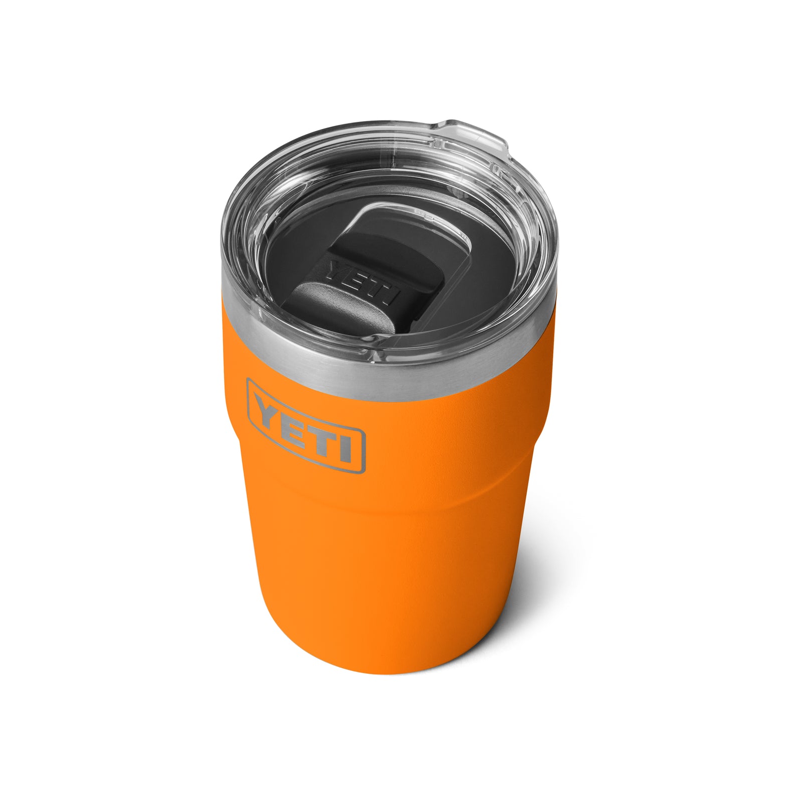 Der YETI® Rambler 16 Oz Stapelbarer Becher - King Crab, ein isolierter, leuchtend orangefarbener Becher mit durchsichtigem Deckel und verschiebbarem schwarzem Mundstück, steht auf einem weißen Hintergrund.
