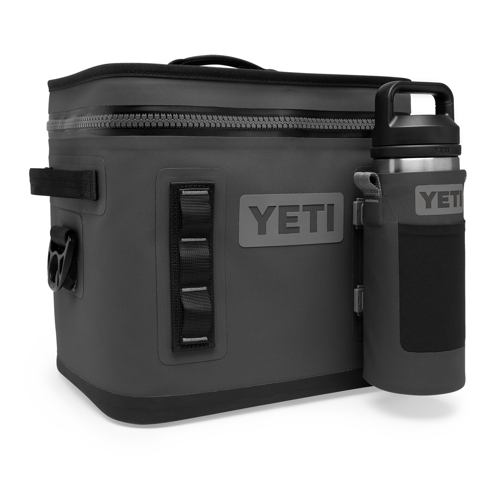 Ein anthrazitfarbener YETI® Rambler Bottle Sling Small, der als Getränkehalter verwendet wird, ist an einer dunkelgrauen YETI Soft-Side-Kühltasche mit Reißverschluss oben und seitlichem Griff befestigt, die vor einem weißen Hintergrund abgebildet ist.