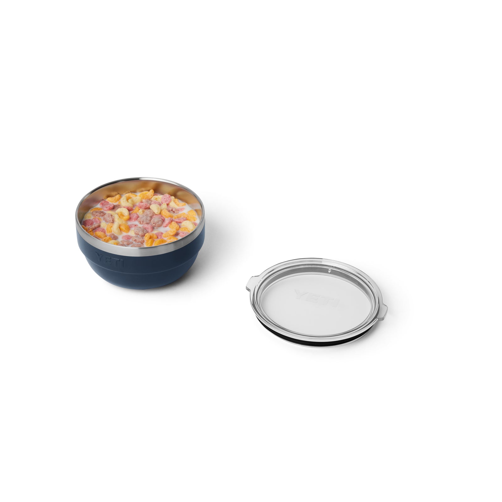 Die YETI® Rambler Bowl Small in Marineblau mit doppelwandiger Vakuumisolierung ist mit buntem Müsli und Milch gefüllt. Die Schale steht neben ihrem durchsichtigen Kunststoffdeckel auf einem weißen Hintergrund.