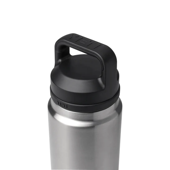 Die YETI® Rambler Flasche von YETI besteht aus bruchsicherem Edelstahl und hat einen schwarzen Schraubdeckel mit stabilem Henkel, der auf einem schlichten hellgrauen Hintergrund steht.