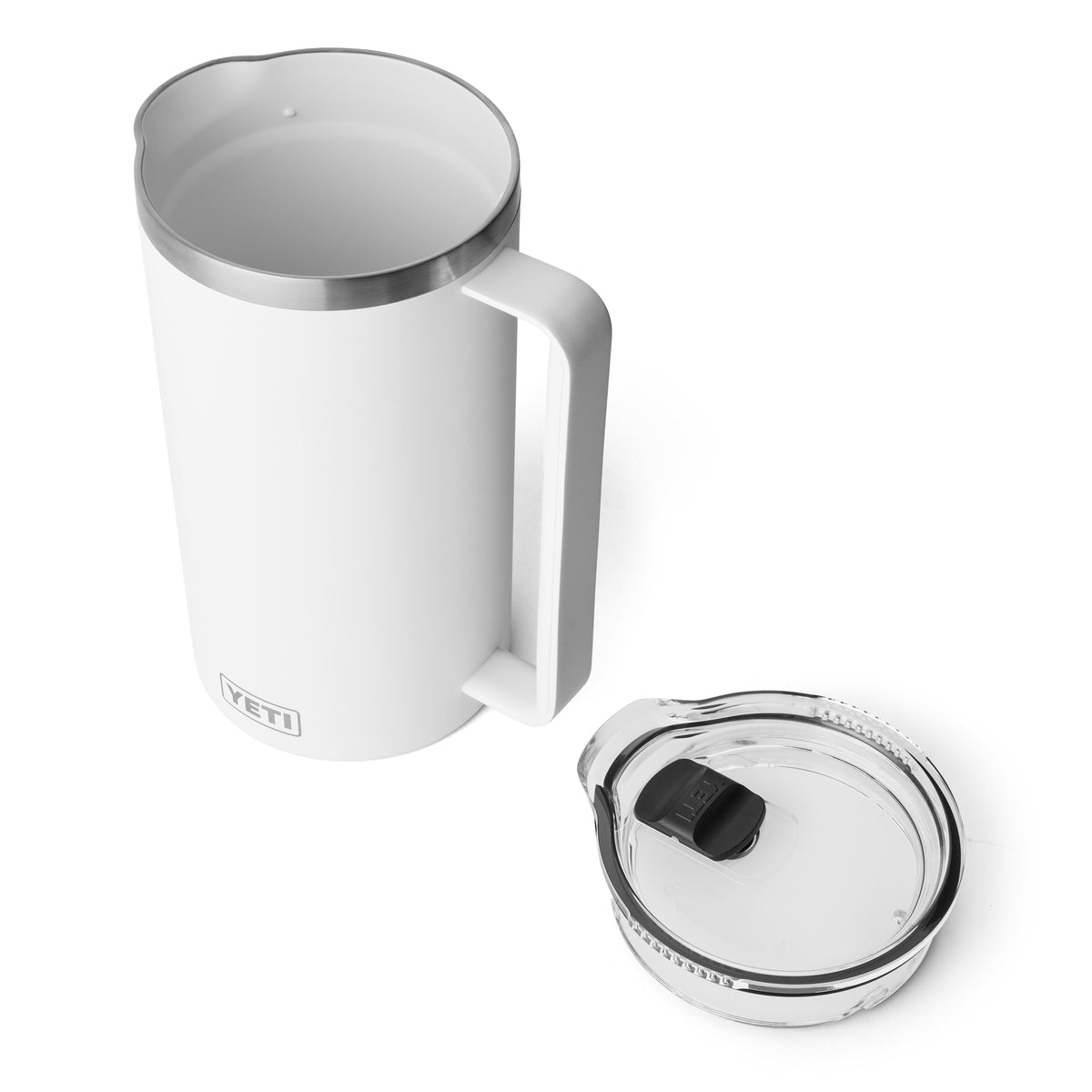 Ein weißer YETI® Rambler Pitcher 64 Oz steht auf einer weißen Oberfläche neben seinem transparenten Deckel und verfügt über einen leicht zu greifenden Griff - ideal, um Getränke während Ihrer Outdoor-Abenteuer kalt zu halten.
