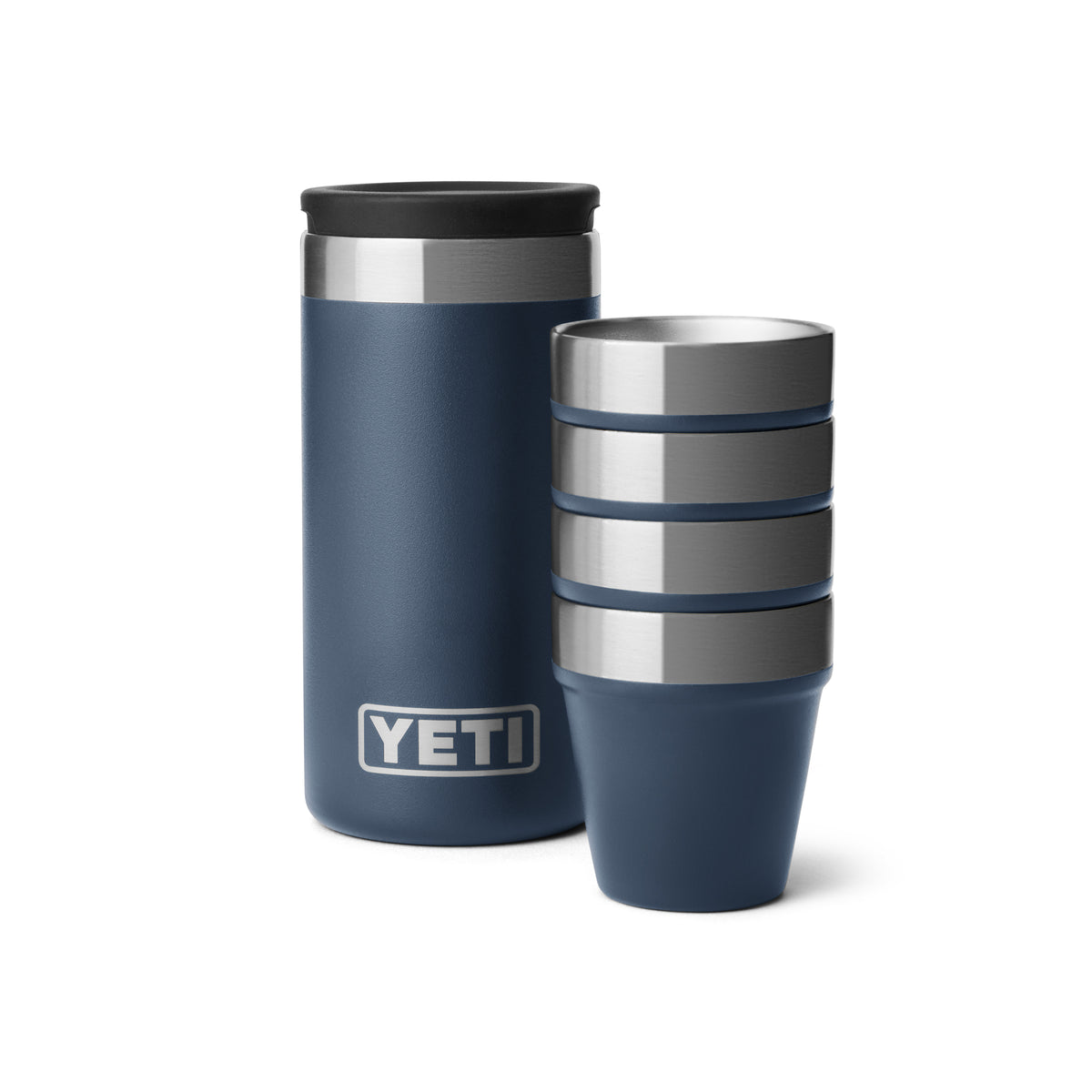 Ein navyfarbener YETI® Rambler Schnapsbecher steht neben einem Stapel von vier passenden vakuumisolierten Schnapsbechern aus Edelstahl, die alle mit dem YETI-Logo versehen sind.