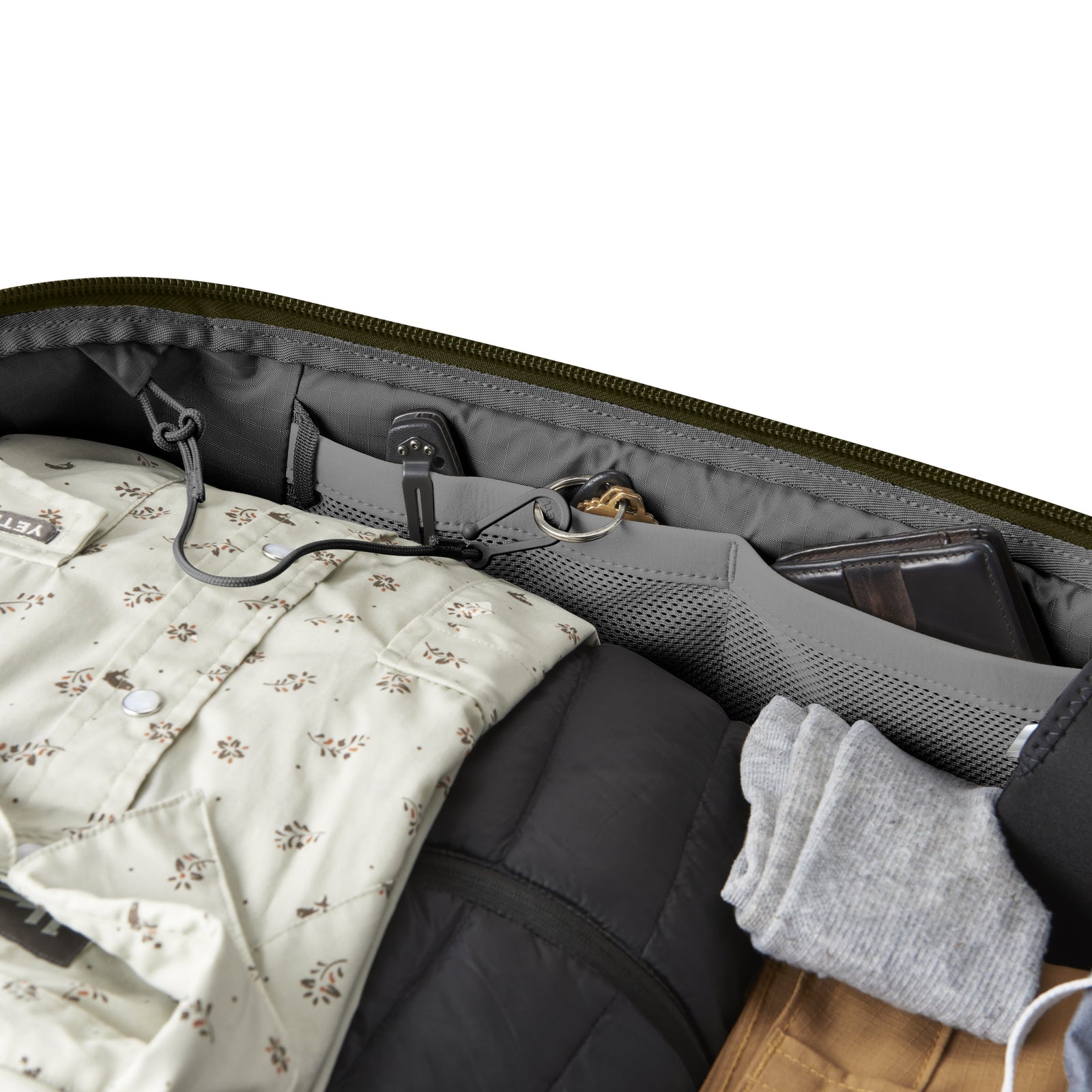 Eine geöffnete YETI® Reisetasche Crossroads® 40L - Olive zeigt ordentlich verpackte Kleidung und kleine Gegenstände wie Brieftasche, Kabel und Stift, die in Netztaschen innerhalb des strapazierfähigen TuffSkin™ Nylon-Futters organisiert sind.