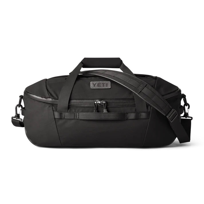 Die YETI® Reisetasche Crossroads 40 L in Schwarz ist aus strapazierfähigem TuffSkin-Nylon gefertigt und verfügt über kurze Griffe, einen abnehmbaren Schultergurt, eine Reißverschlusstasche auf der Vorderseite und einen kleinen YETI-Logoaufnäher. Fotografiert vor einem weißen Hintergrund.