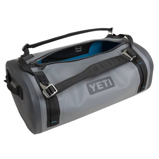 Die YETI® Reisetasche Panga 50 in Storm Grey von YETI mit schwarzen Tragegurten und Henkeln ist auf einem weißen Hintergrund zu sehen; sie ist teilweise geöffnet und zeigt ein blaues Innenfutter.