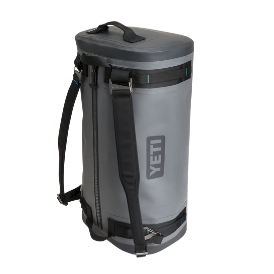 Die zylindrische YETI® Reisetasche Panga 50 in sturmgrau ist vom robusten YETI®-Design inspiriert und verfügt über schwarze Riemen, einen seitlichen Reißverschluss, ein YETI-Logo auf der Vorderseite und einen stabilen Griff.