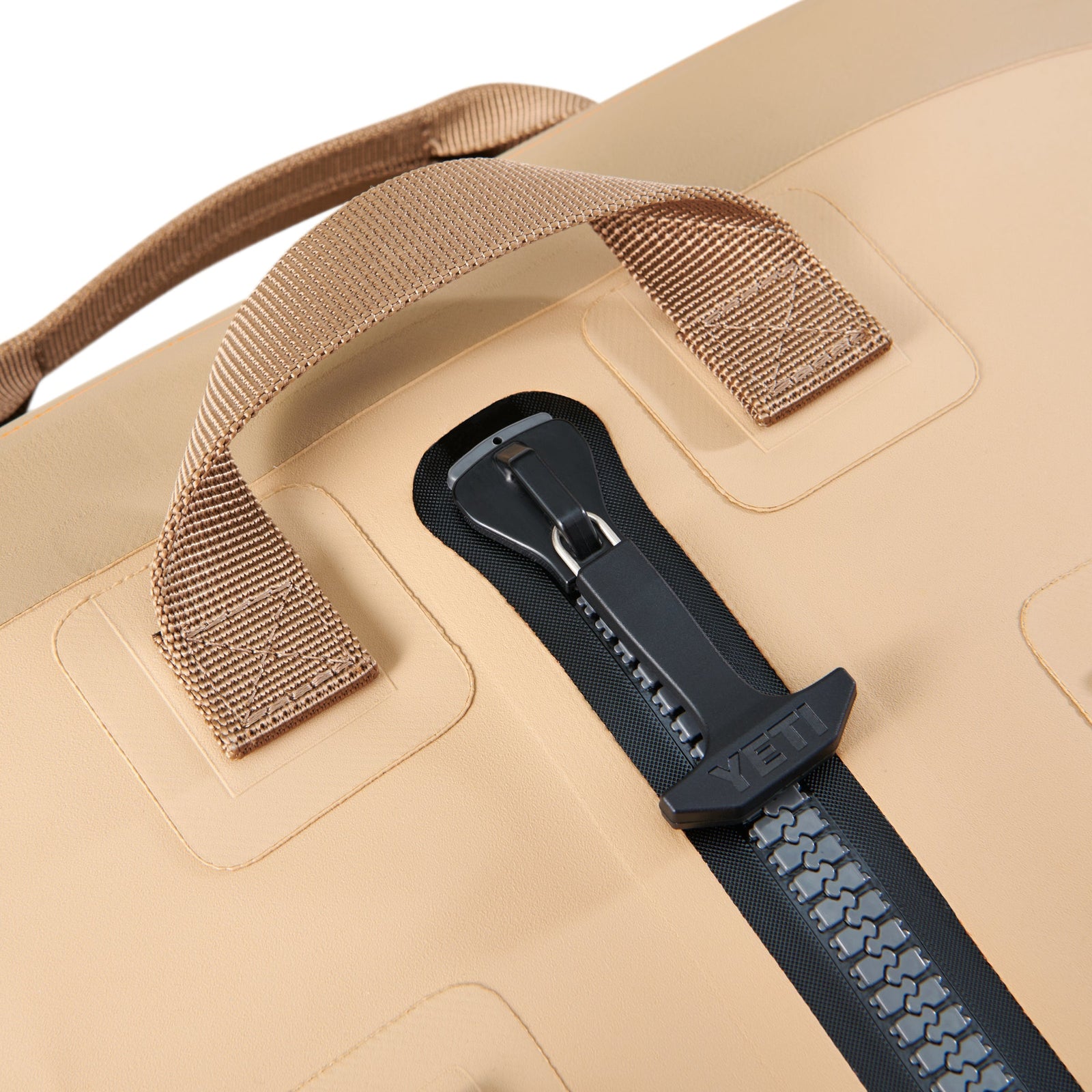 Nahaufnahme der YETI® Reisetasche Panga 75 - Tan mit robusten gewebten Griffen und einem großen schwarzen Reißverschluss. Das haltbare, wasserdichte Material macht sie ideal für Outdoor-Abenteuer.