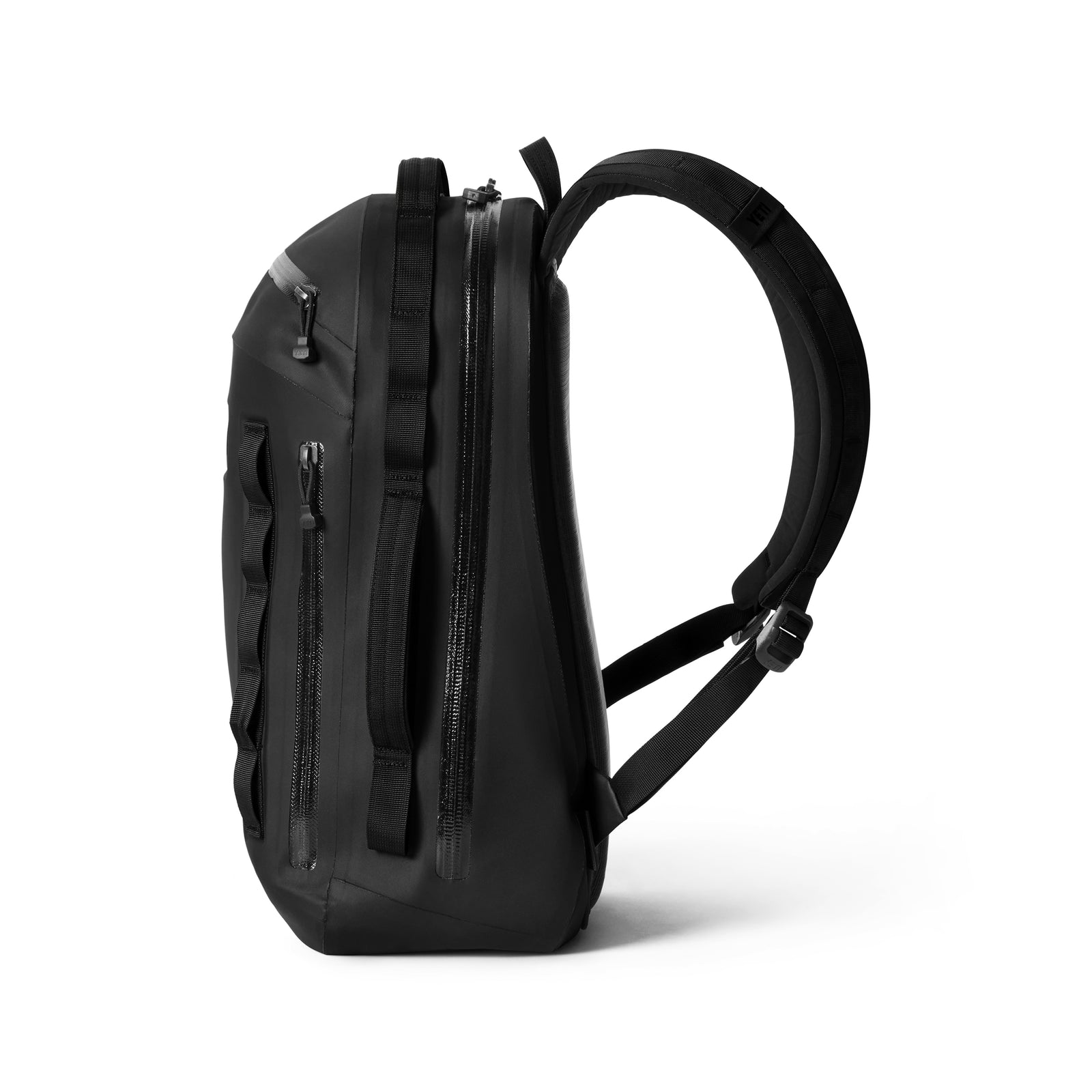 Der YETI® Rucksack Cayo™ 25L in Schwarz wird von der Seite gezeigt und hebt sein minimalistisches Design, mehrere Reißverschlussfächer und verstellbare, gepolsterte Schultergurte vor einem weißen Hintergrund hervor.