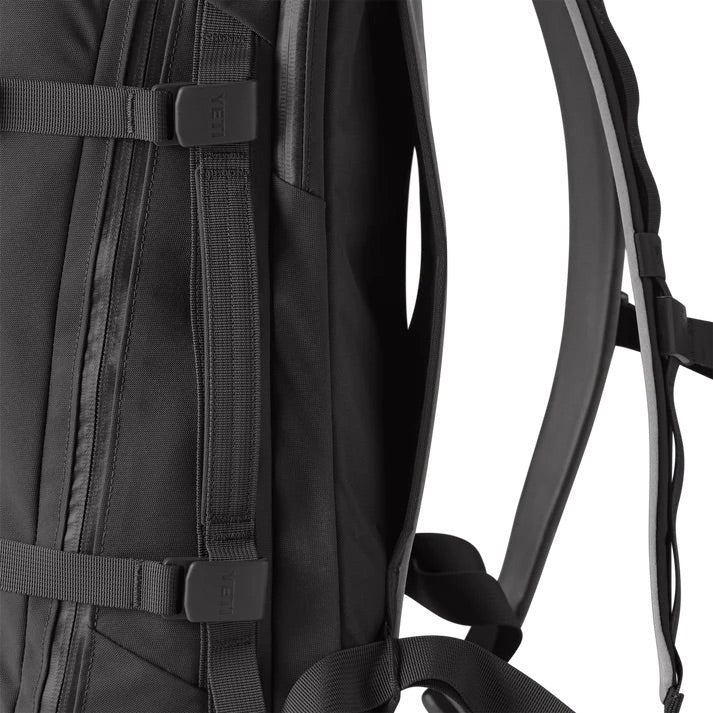 Nahaufnahme des YETI® Rucksack Crossroads® 27L in Schwarz. Hervorzuheben sind die gepolsterten Schultergurte, die seitlichen Kompressionsschnallen, die robusten Nähte, ein spezielles Laptop-Fach, das strapazierfähige Material und das schlichte, moderne Design.
