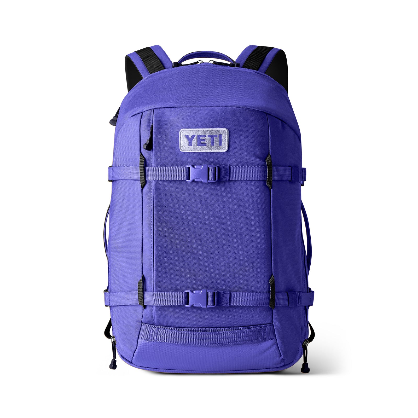 Der YETI® Crossroads® 27L Rucksack in Ultramarinblau verfügt über schwarze Riemen und Schnallen, ein geräumiges Hauptfach, zwei horizontale Riemen auf der Vorderseite und einen YETI-Logoaufnäher auf der oberen Vordertasche, alles vor einem weißen Hintergrund.