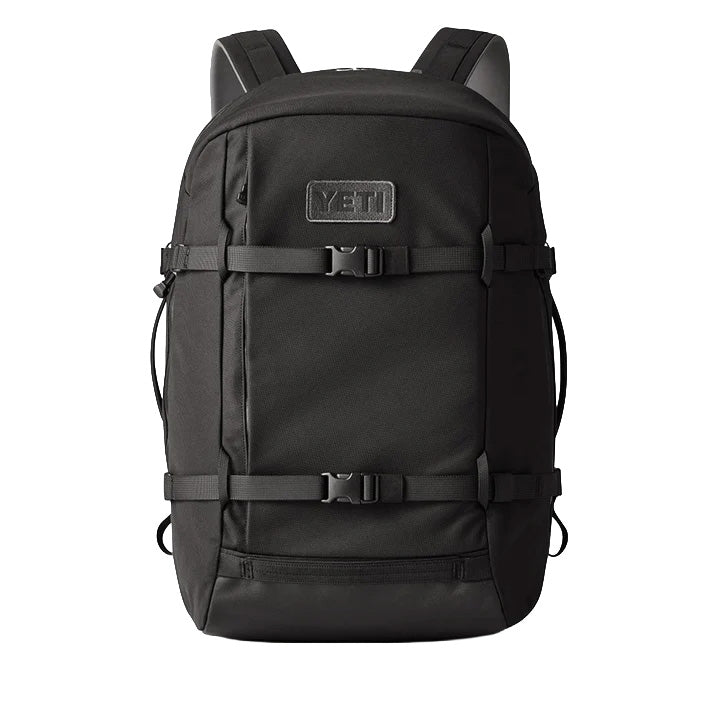 Der YETI® Rucksack Crossroads® 35L - Black verfügt über gepolsterte Schultergurte, zwei Schnallengurte an der Vorderseite, seitliche Kompressionsschnüre, ein gesticktes YETI-Logo auf der Vordertasche und ein geräumiges Laptopfach.