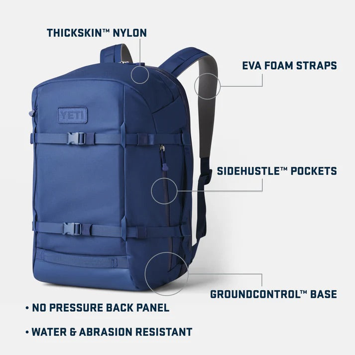 Ein schwarzer YETI Crossroads 35L Rucksack mit Etiketten, die ThickSkin-Nylon, EVA-Schaumgurte, SideHustle-Taschen, GroundControl-Boden, druckfreies Rückenteil, Wasser- und Abriebfestigkeit und ein spezielles Laptop-Fach zeigen.