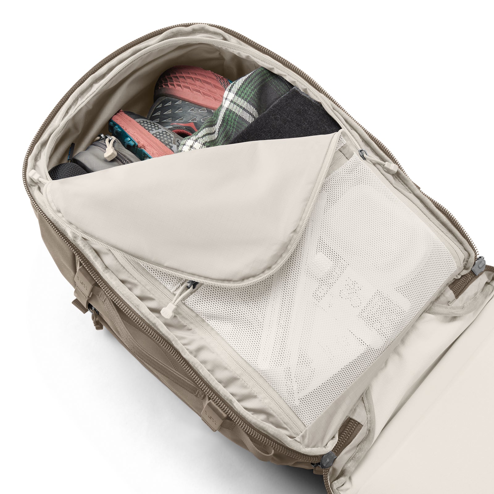 Ein marineblauer YETI® Rucksack Crossroads® 35L ist geöffnet und gibt den Blick auf ordentlich gepackte Gegenstände frei: Turnschuhe, ein kariertes Hemd, ein dunkles Kleidungsstück und andere wichtige Dinge, die durch die Netztasche mit Reißverschluss sichtbar sind.