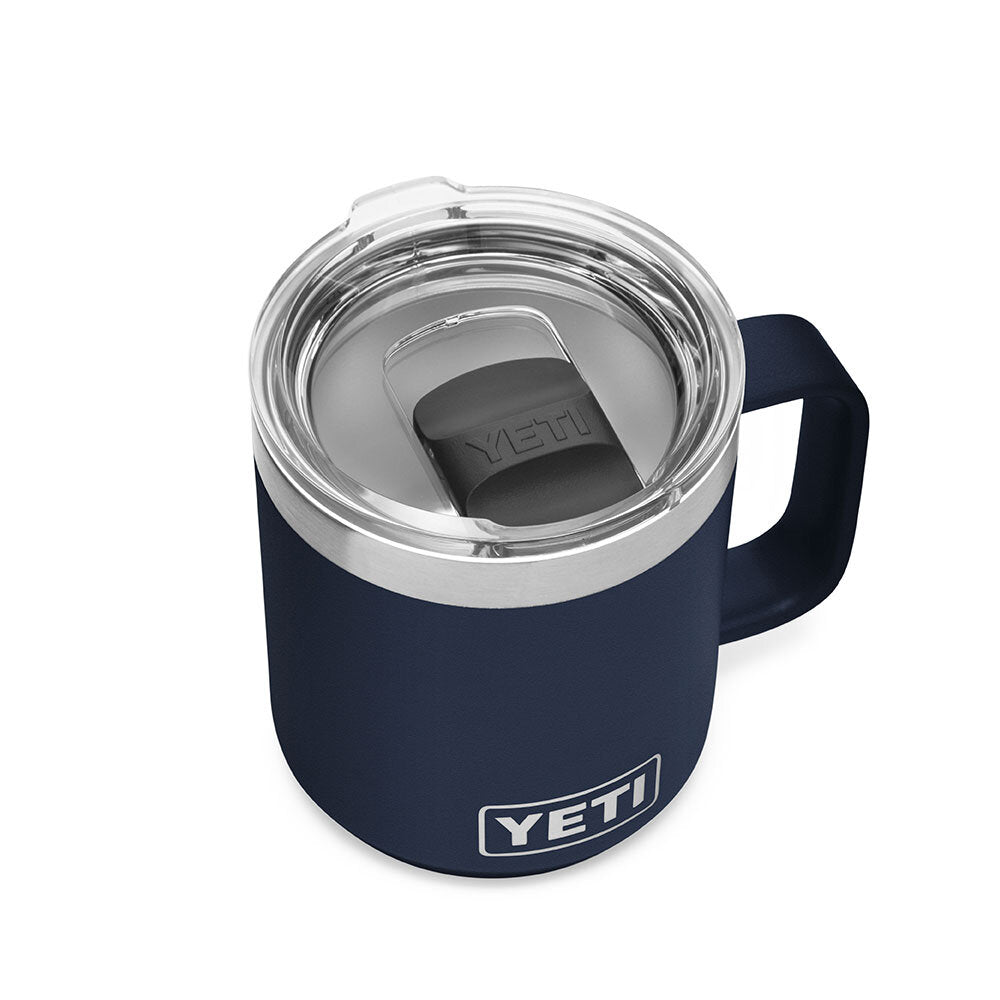 Der YETI® Tasse Rambler 10 Oz in Navy mit stabilem Griff und transparentem, auslaufsicherem Deckel steht auf einem weißen Hintergrund. Das YETI-Logo prangt auf der Vorderseite dieses Kaffeebechers aus Edelstahl.