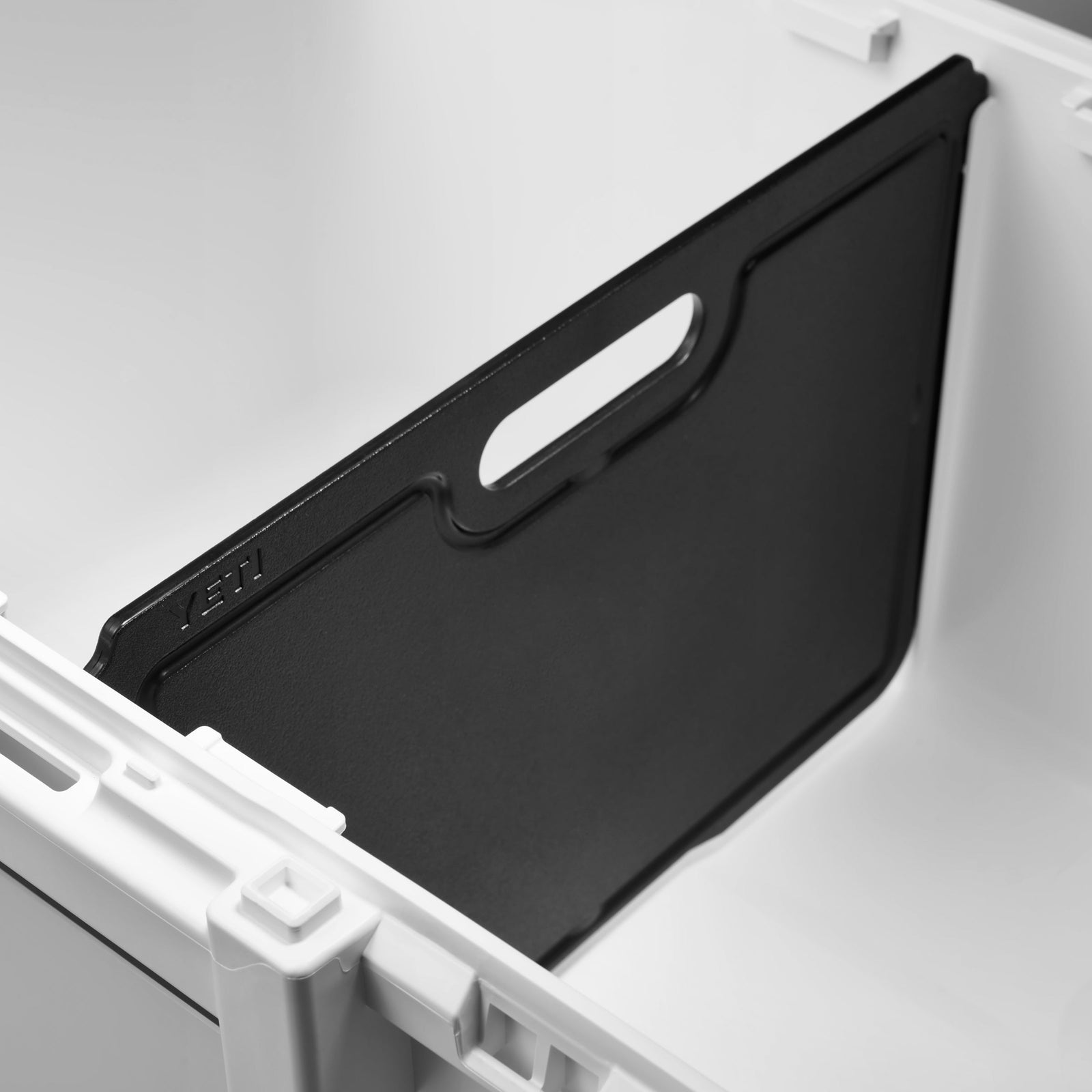Die Nahaufnahme einer weißen LoadOut GoBox 30 zeigt eine herausnehmbare schwarze YETI® Trennwand zu LoadOut GoBox 30 mit Griffaussparung, die für optimale Organisation und flexible Inneneinteilung vertikal angeordnet ist.