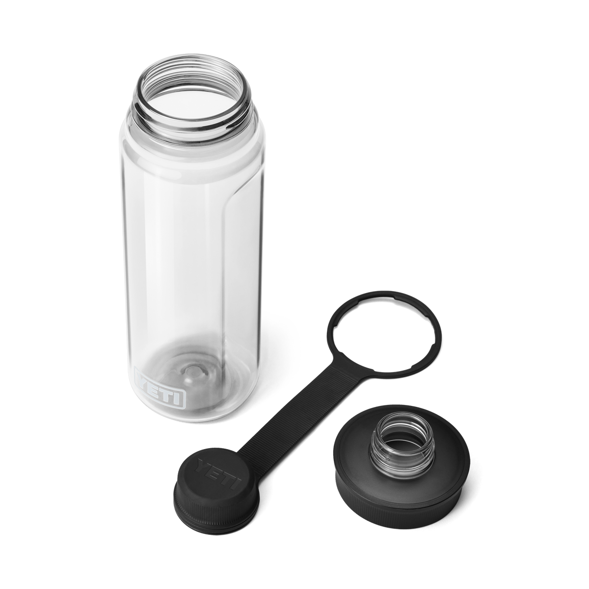 Eine klare YETI® Yonder™ 750ml Wasserflasche von YETI ruht auf einer weißen Oberfläche. Die BPA-freie, auslaufsichere Flasche hat eine große Öffnung und zwei schwarze, abnehmbare Deckel: einen Schraubverschluss und einen Spout Cap mit Riemen.