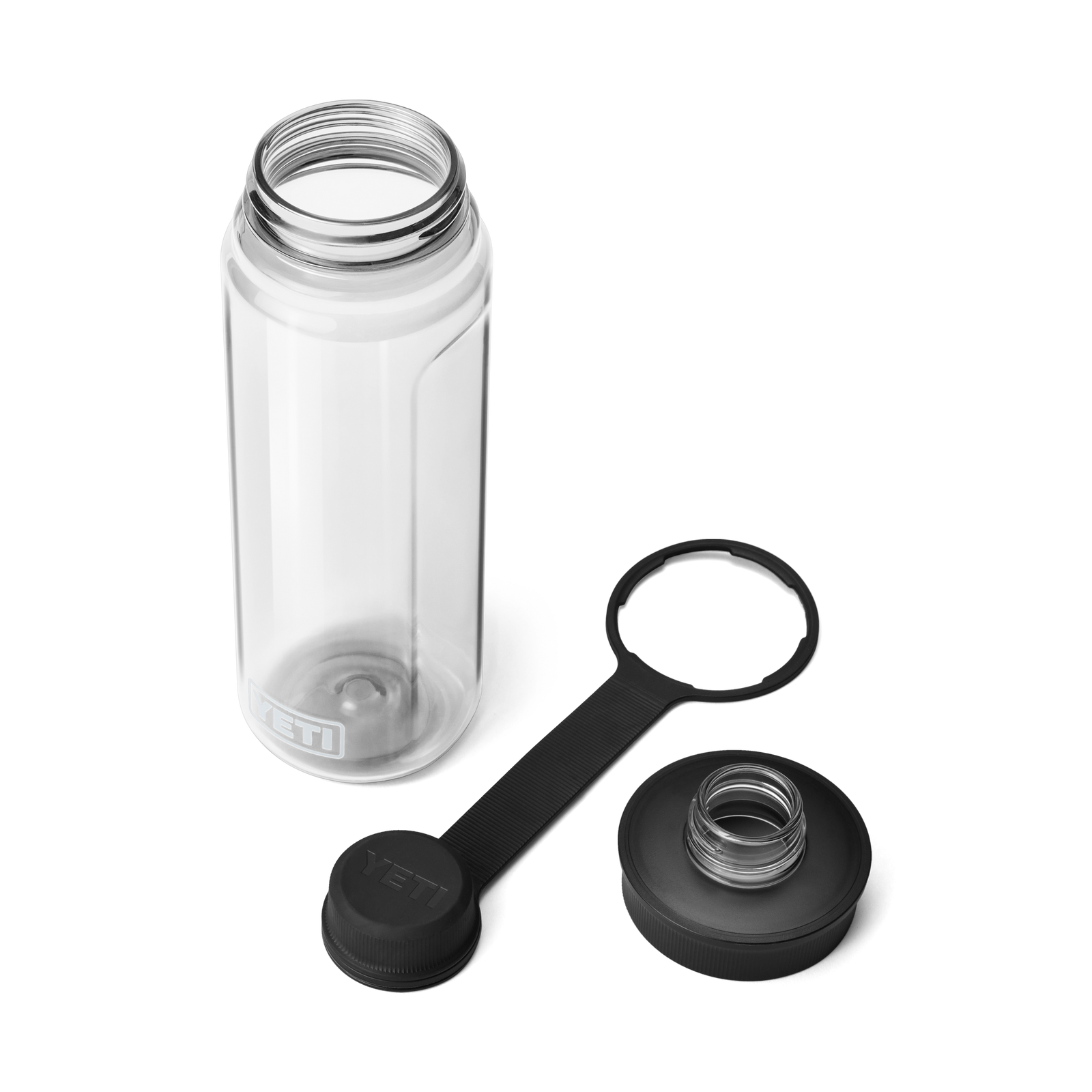 Eine klare YETI® Yonder™ 750ml Wasserflasche von YETI ruht auf einer weißen Oberfläche. Die BPA-freie, auslaufsichere Flasche hat eine große Öffnung und zwei schwarze, abnehmbare Deckel: einen Schraubverschluss und einen Spout Cap mit Riemen.