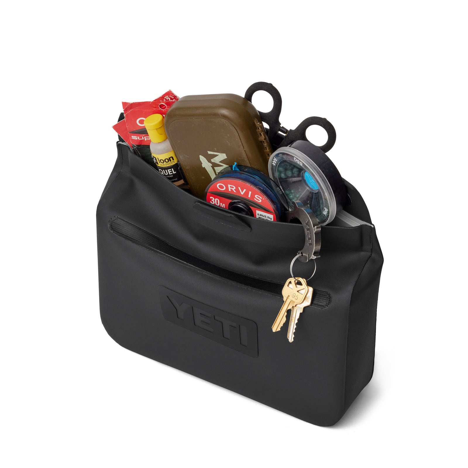 Eine schwarze YETI® Zubehörtasche - Sidekick® 3L, vollgepackt mit Angelutensilien wie Spulen, Scheren, Schläuchen und Paketen; im Inneren befindet sich ein braunes Etui, während zwei Schlüssel an einem Ring am Reißverschluss dieser wasserdichten Tasche befestigt sind.